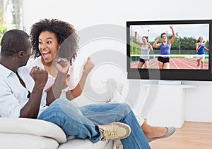 Excited couple cheering and watching a sports in television