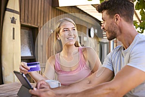 Excited Couple With Credit Card Using Digital Tablet At Home To Book Holiday Or Shop Online