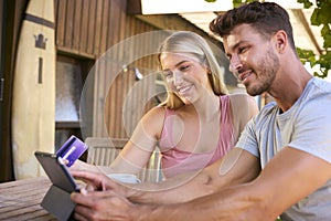 Excited Couple With Credit Card Using Digital Tablet At Home To Book Holiday Or Shop Online