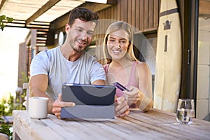 Excited Couple With Credit Card Using Digital Tablet At Home To Book Holiday Or Shop Online