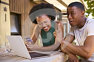 Excited Couple With Credit Card Using Laptop At Home To Book Holiday Or Shop Online