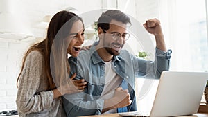 Excited couple feel euphoric reading good news on laptop online