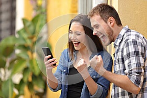 Excited couple finding online offers on phone in the street photo