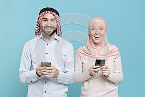 Excited couple friends arabian muslim man wonam in keffiyeh kafiya ring igal agal hijab clothes isolated on blue photo
