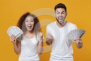 Excited couple friends european guy african american girl in white t-shirts isolated on yellow background. People