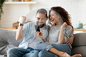 Excited couple holding smartphone celebrating online lottery win