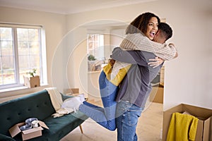 Excited Couple Hugging As They Unpack Boxes In New Home On Moving Day