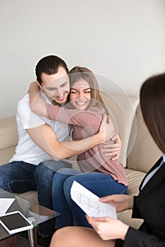 Excited couple hugging on meeting with estate agent, mortgage in