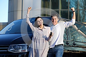 Excited couple with key near car. Buying new auto