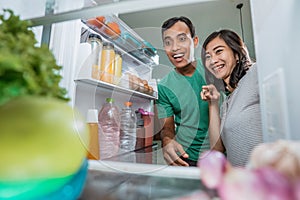 excited couple open the fridge in the kitchen preparing to cook together