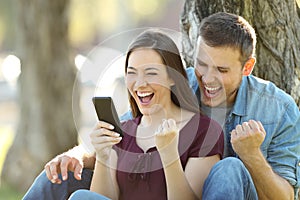 Excited couple reading news in a phone