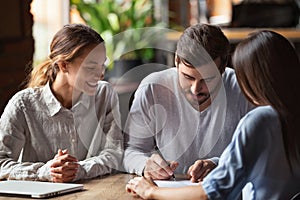 Excited couple sign agreement closing deal with realtor