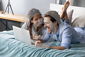 Excited couple triumph celebrate online win on laptop