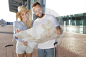 Excited couple using map and searching sightseeings to visit