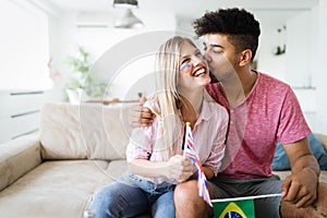 Excited couple watching tv together sitting on a sofa in the living room