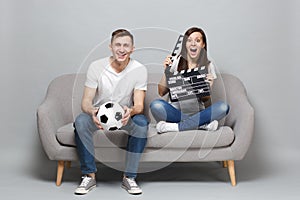 Excited couple woman man football fans cheer up support favorite team with soccer ball holding classic black film making