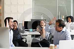 Excited coworkers celebrate shared business win in office