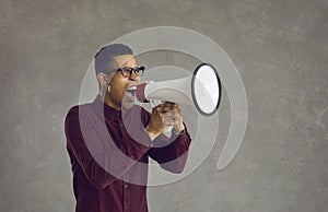 An excited crazy angry young African American man loudly shouting in a megaphone