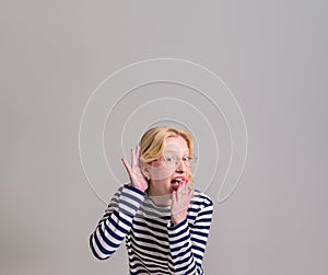 Excited curious young woman covering her mouth and listening secret on isolated white background