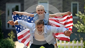 Excited dad and girl patriots having fun, holding USA flag, family immigration