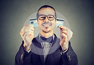 Excited debt free business man in glasses holding a credit card cut in two pieces