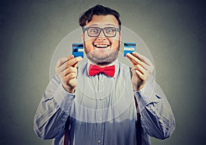 Excited debt free business man in glasses holding a credit card cut in two pieces