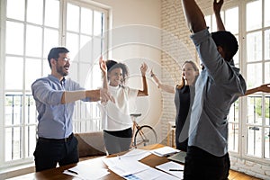 Excited diverse business people celebrating business achievement at meeting