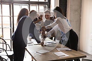 Excited diverse business people stacking fists at table, team building