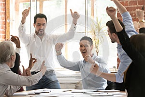 Excited diverse colleagues celebrate team win in office