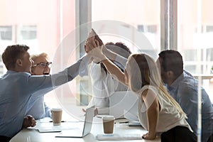 Excited diverse colleagues give high five at meeting