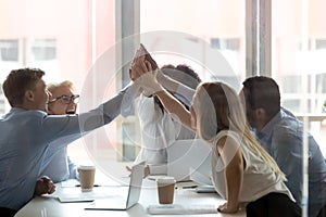 Excited diverse colleagues give high five at meeting photo