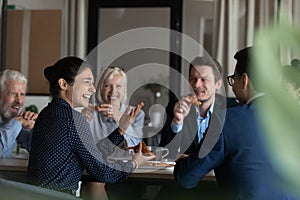 Excited diverse employees eating pizza during break in office together