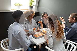 Excited diverse employees team eating pizza at lunch break