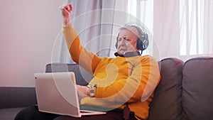 Excited elderly man with headset gambling online and winning