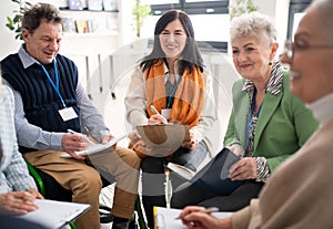 Excited elderly people attending group therapy session at nursing house, positive senior man and woman sitting in circle
