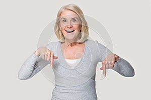 Excited elderly woman head shot showing with her fingers down