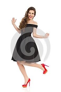 Excited Elegant Woman In Black Dress Is Dancing On One Leg