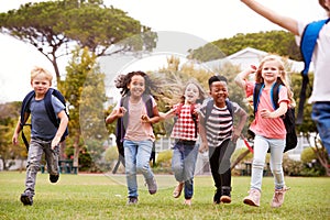 Excited Elementary School Pupils Running Across Field At Break Time