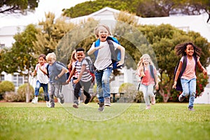 Excited Elementary School Pupils Running Across Field At Break Time