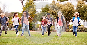 Excited Elementary School Pupils Running Across Field At Break Time