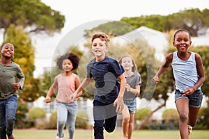 Excited Elementary School Pupils Running Across Field At Break Time