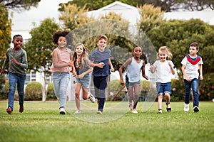 Excited Elementary School Pupils Running Across Field At Break Time