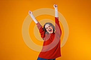 Excited emotional happy young pretty woman posing isolated over yellow wall background