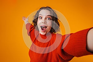 Excited emotional happy young pretty woman posing isolated over yellow wall background