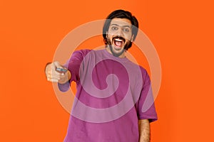 Excited emotional young eastern man holding TV remote control