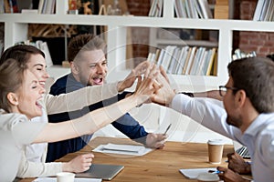 Excited employees give high five celebrating shared success