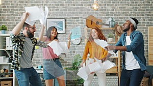 Excited employees young people dancing at office party holding business contract