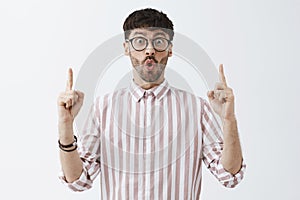 Excited enthusiastic good-looking mature guy with beard folding lips and staring with excitement and amazement at camera