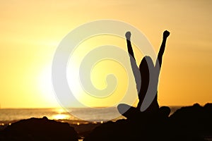 Excited euphoric woman looking sun at sunrise photo