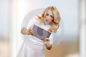 Excited expressive mature blonde woman holds digital tablet pc in both hands.